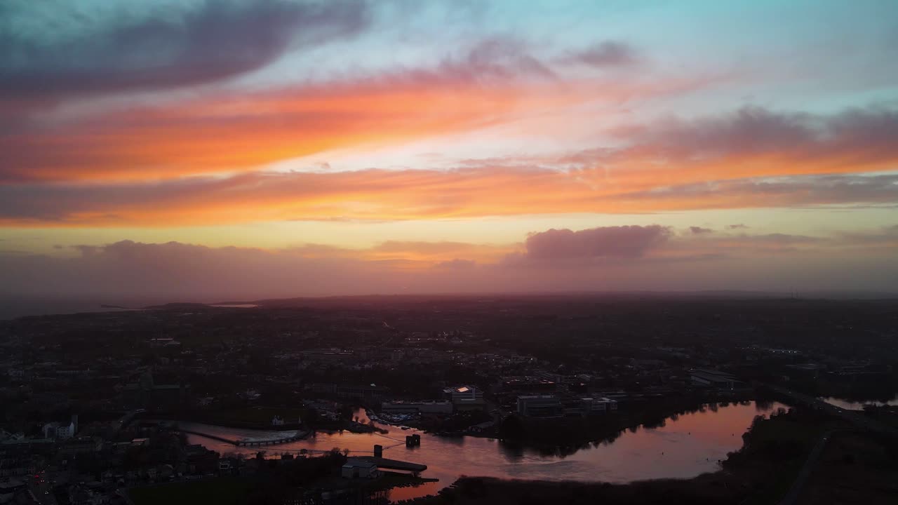 川に美しい空が反射する、ゴールウェイ市の上空のかすんだ夕日のドローン空撮