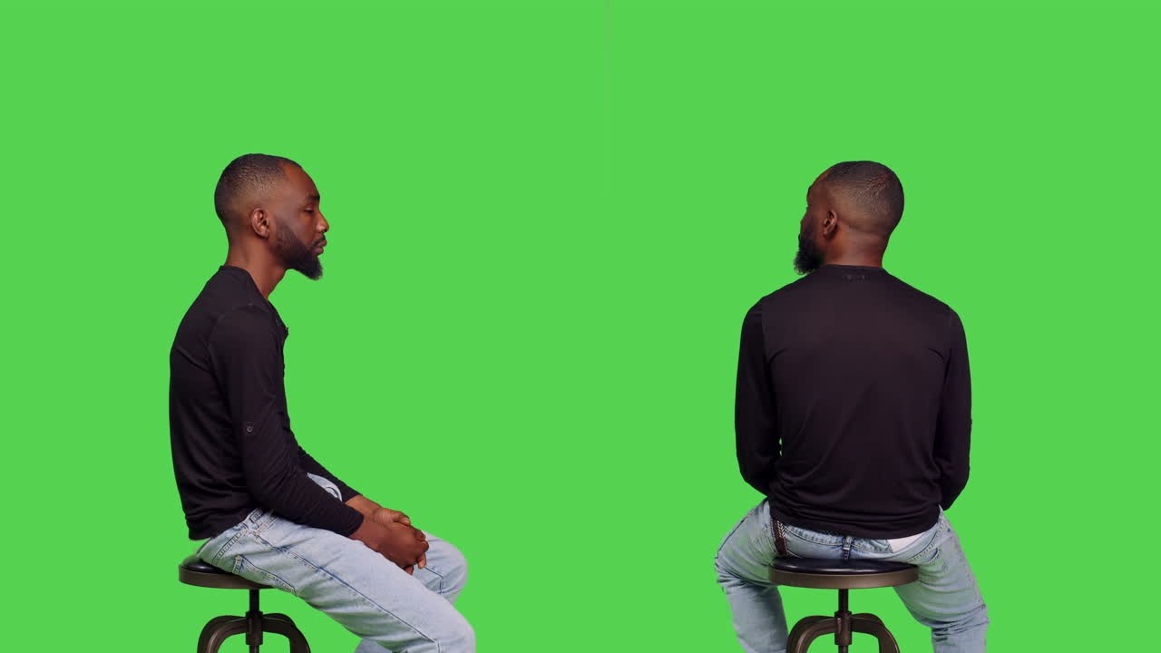 Man sitting on a stool in front of a green screen