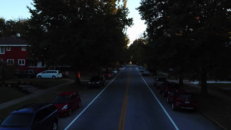 Aerial-view-down-middle-of-residential-street-with-cars-parked-on-side-of-road