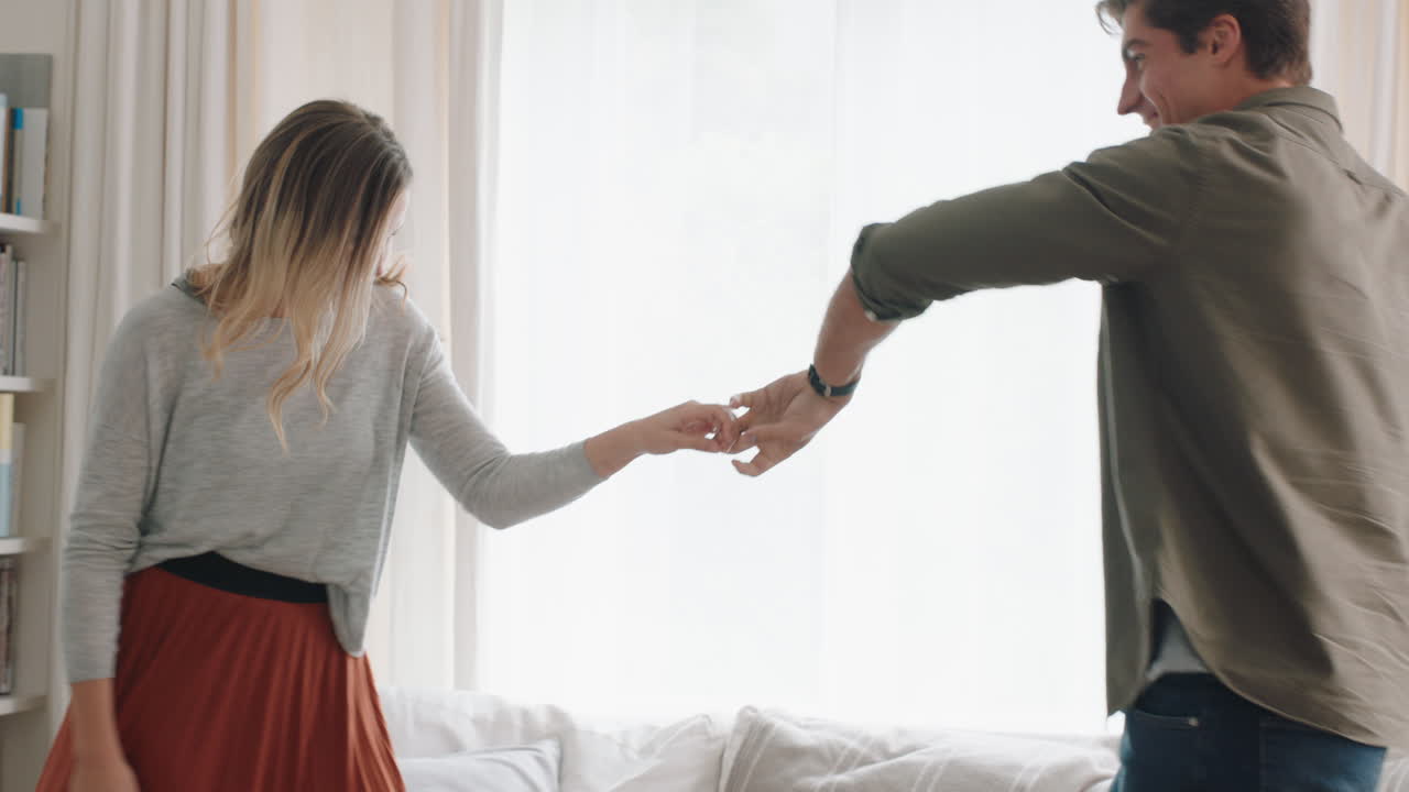 una pareja joven feliz bailando juntos en casa celebrando divirtiéndose el fin de semana sonriendo disfrutando de un baile divertido en la sala de estar celebrando una relación exitosa imágenes en 4k