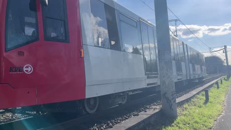 Tram-drives-past-the-camera-over-rails-that-lie-on-a-field-in-good-light-and-good-weather