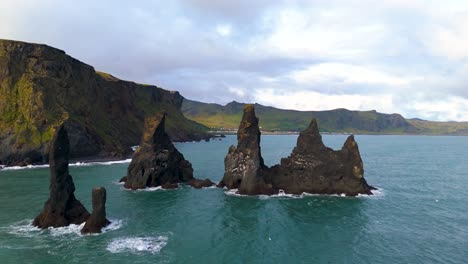 Huge-rocky-peaks-rise-from-the-middle-of-the-sea-in-Iceland-on-the-black-sand-beach-of-Reynisfjara