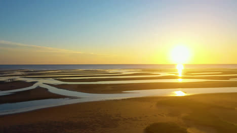 cape cod bay beach at low tide during golden hour, bright sun low and setting, pan right