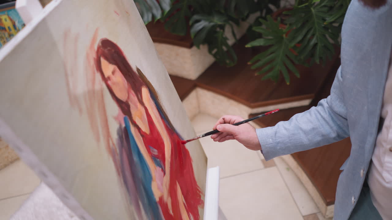 el artista agrega color rojo al vestido en el lienzo. el pintor elige colores y sombras que dictan el estado de ánimo y la atmósfera del retrato en evolución. el pintor intuitivo