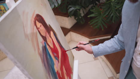 artist adds red color to dress on canvas. painter chooses colors and shadings dictating mood and atmosphere of evolving portrait. painter intuitive