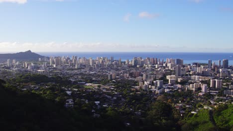 drone disparó panorámica a la izquierda a través de la ciudad de honolulu hawai con el océano pacífico en el fondo y el cielo azul desde un punto de vista de la montaña en oahu