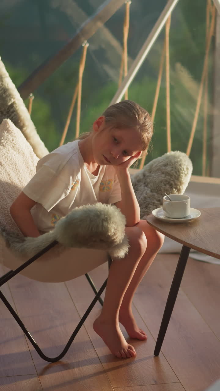 Sleepy children rest sitting at table in early morning. Little boy and girl drink tea in tent at resort in nature reserve. Summer family vacation