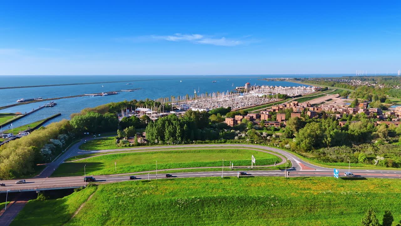Distancing from a large yacht club at the lakefront of Lelystad, the Netherlands. Lots of greenery at the waterscape of Lake Markemeer from aerial perspective.