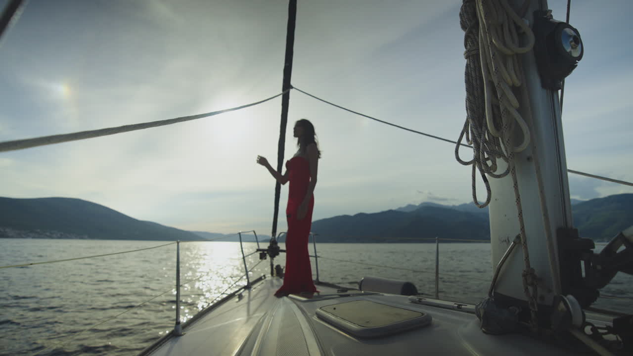 mujer en vestido rojo en un yate al atardecer
