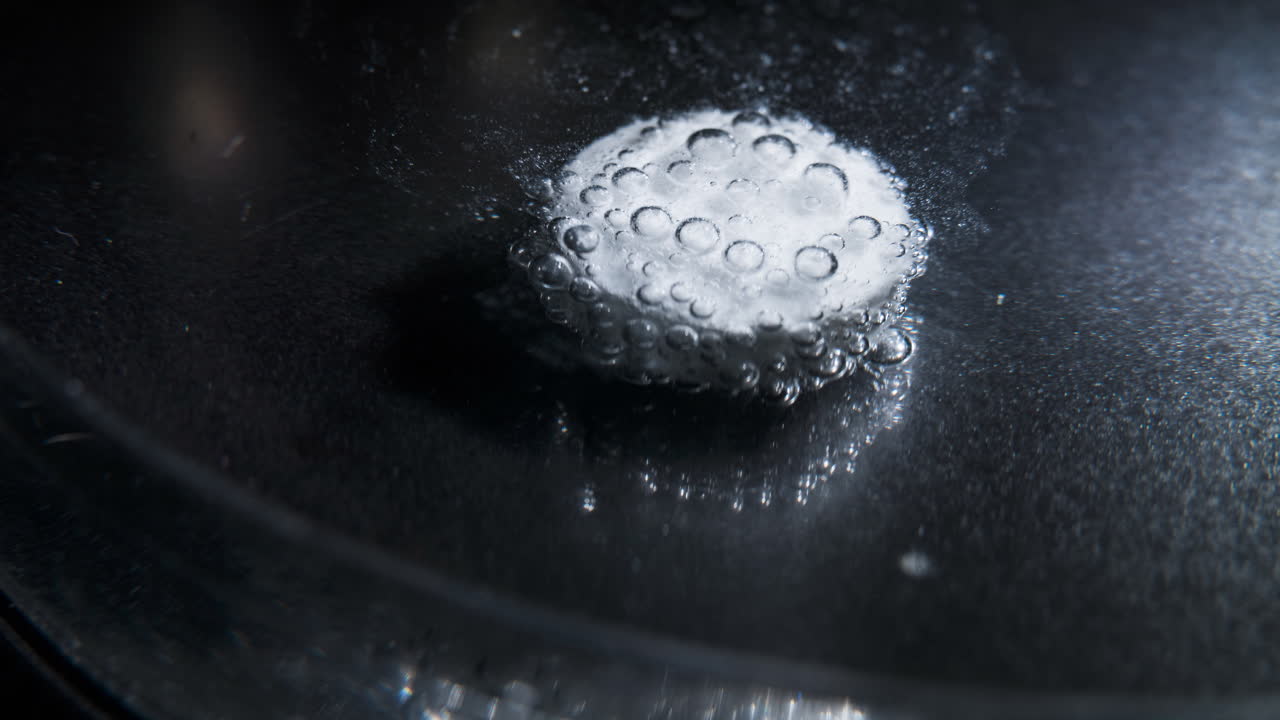 Pill dissolving in liquid, close-up time-lapse of bubbling effervescence