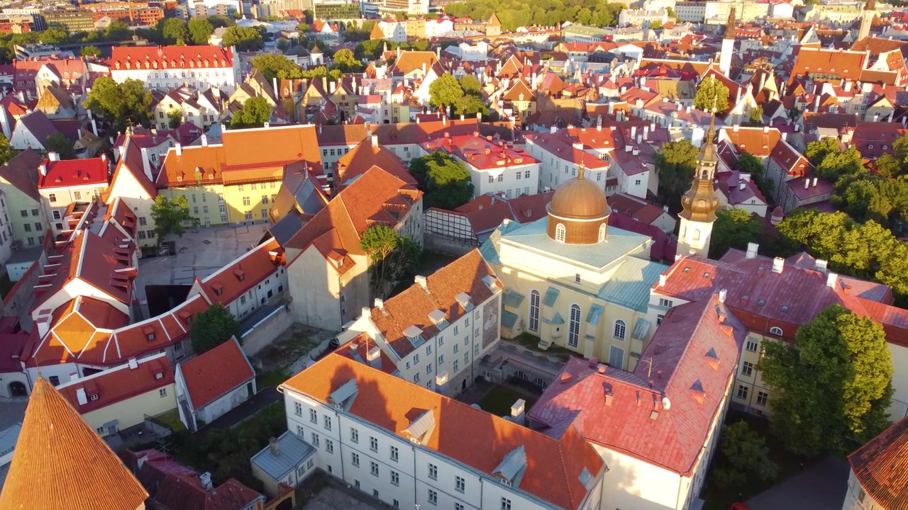 Veduta aerea del centro storico di Tallinn al tramonto, che mostra architettura medievale, tetti rossi ed edifici storici in luce calda