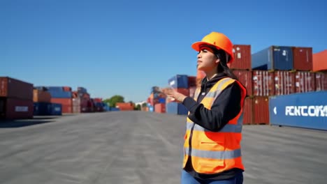 a young professional directing operations in a busy shipping yard, overflowing with colorful containers under a clear blue sky
