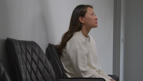 unhappy woman suffering with depression and anxiety sitting in reception of doctor or mental health worker