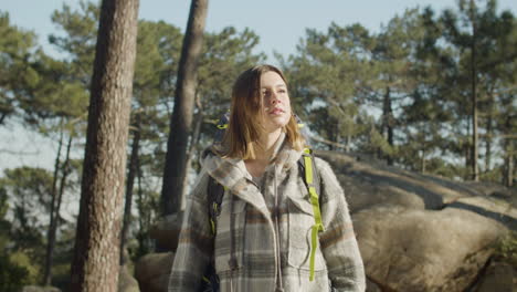 Portrait-Of-A-Brown-Haired-Female-Backpacker-Looking-At-The-Camera-While-Hiking-In-The-Forest-On-A-Sunny-Day