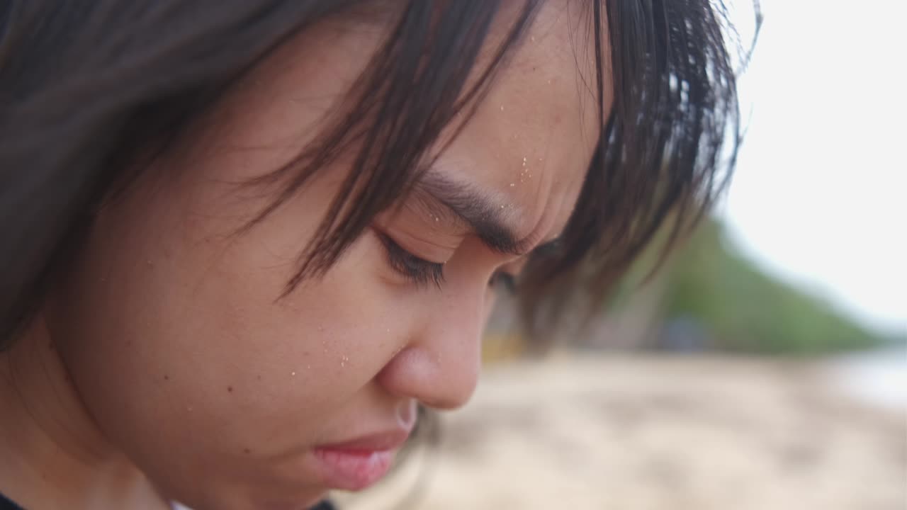 Static close-up portrait of young, depressed woman reflecting and crying at outdoor setting.