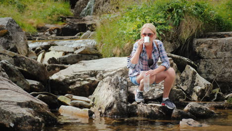 a woman drinks clean water recruited from a stream norway waterfall tvindefossen 4k video