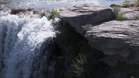 spectral sunlight on whitewater at lip of waterfall with rock overhang