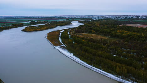 snowy river with mountains in background wide drone shot