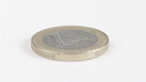 una moneda de euro colocada plana sobre una mesa blanca