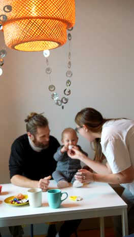 family feeding a baby at a dining table