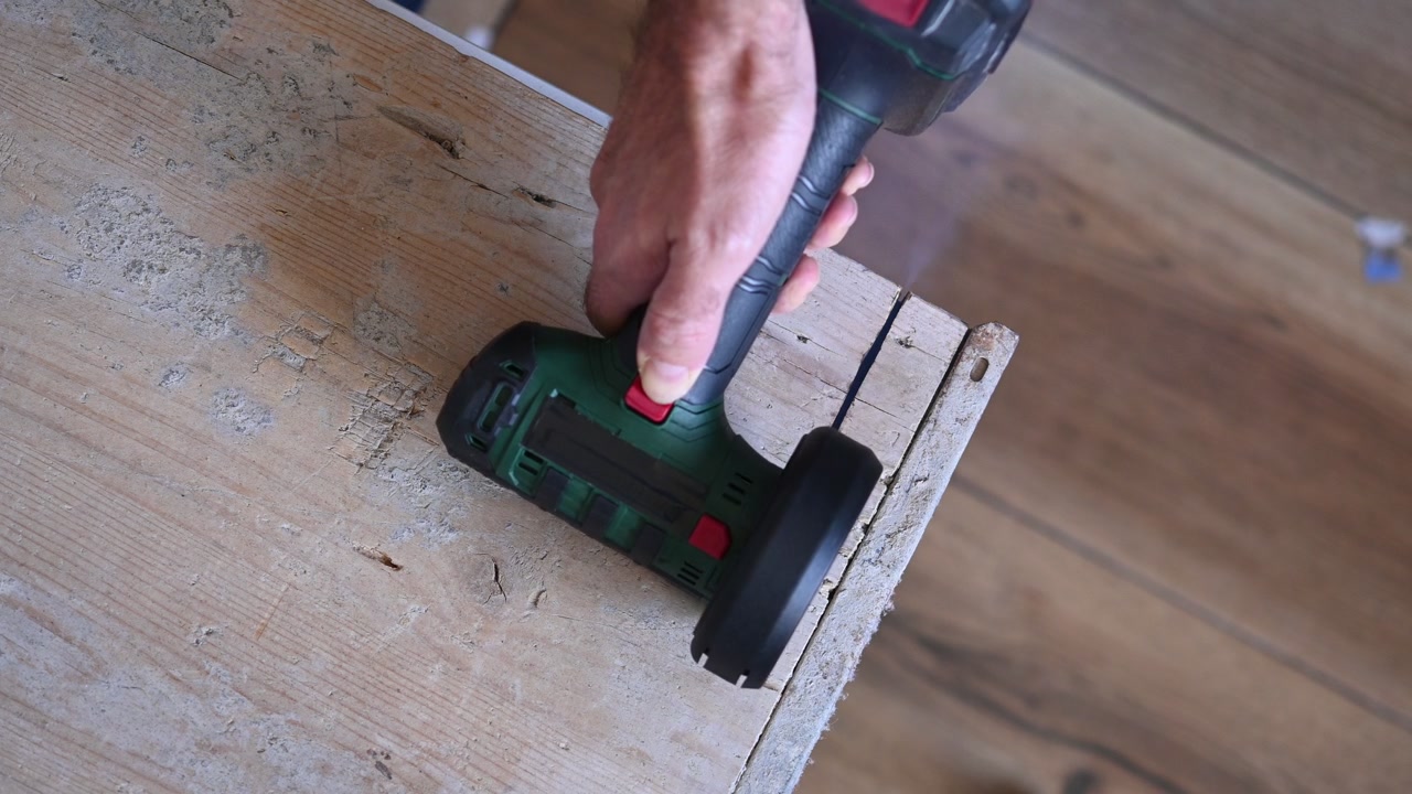 Cordless circular saw cutting wooden board in workshop
