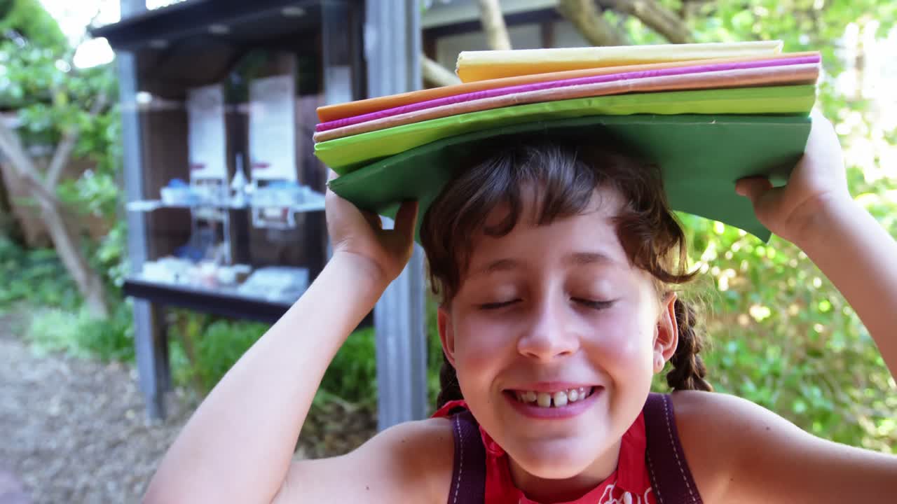 retrato de una estudiante llevando libros por encima de la cabeza en la escuela