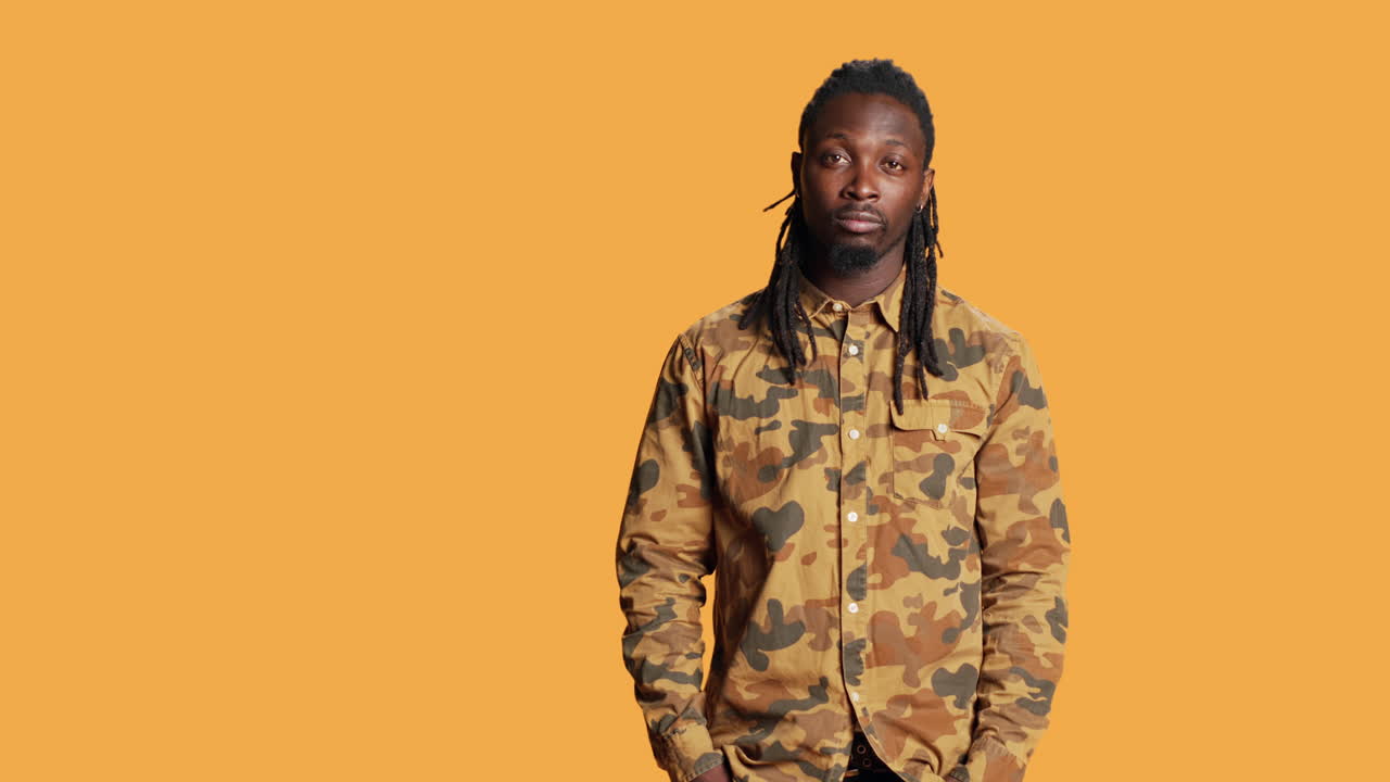 афроамериканский мужчина в камуфляжной рубашке позирует в студии