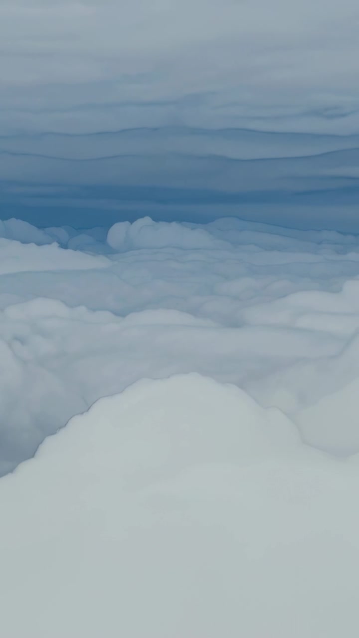 Vertical video: Camera panning above cloud deck, showing cumulus mound, mid clouds, distant bands