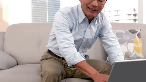 소파에 앉아서 노트북을 사용하는 남자