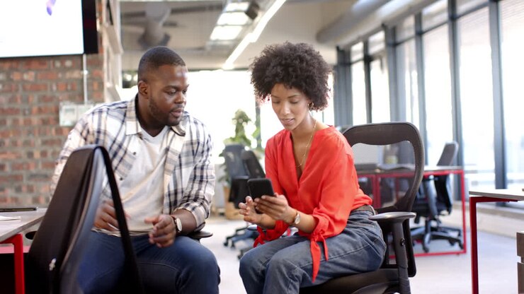 Business man and woman, colleagues in office looking at smartphone together
