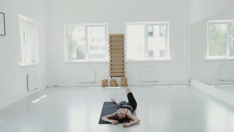 mujer joven estirándose en la alfombra de yoga en el gimnasio