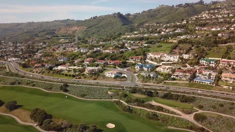 Drone-Shot-of-Mansions-on-the-Rolling-Hills-of-Rancho-Palos-Verdes,-California-on-a-Warm-Day-with-a-Golf-Course-and-the-Pacific-Ocean-in-the-Background