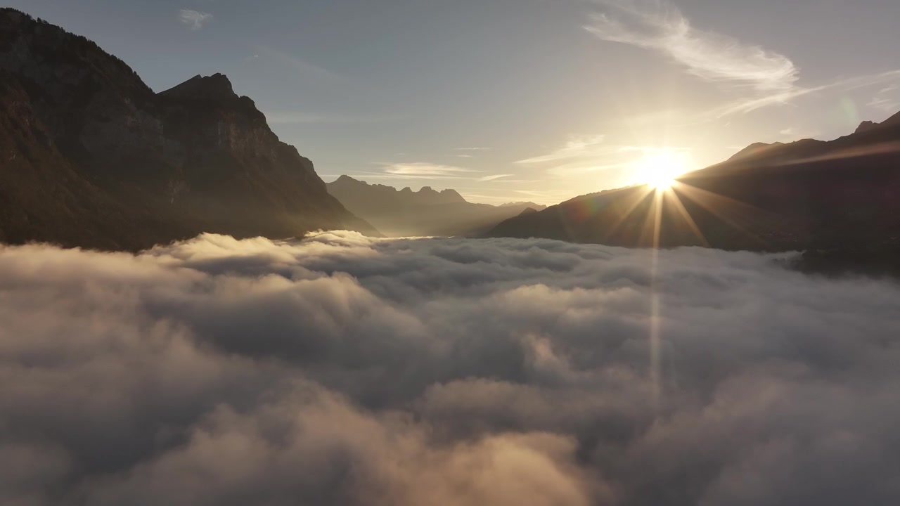 Alba dorata su una valle con nuvole e vette montane in Svizzera, serena e pacifica