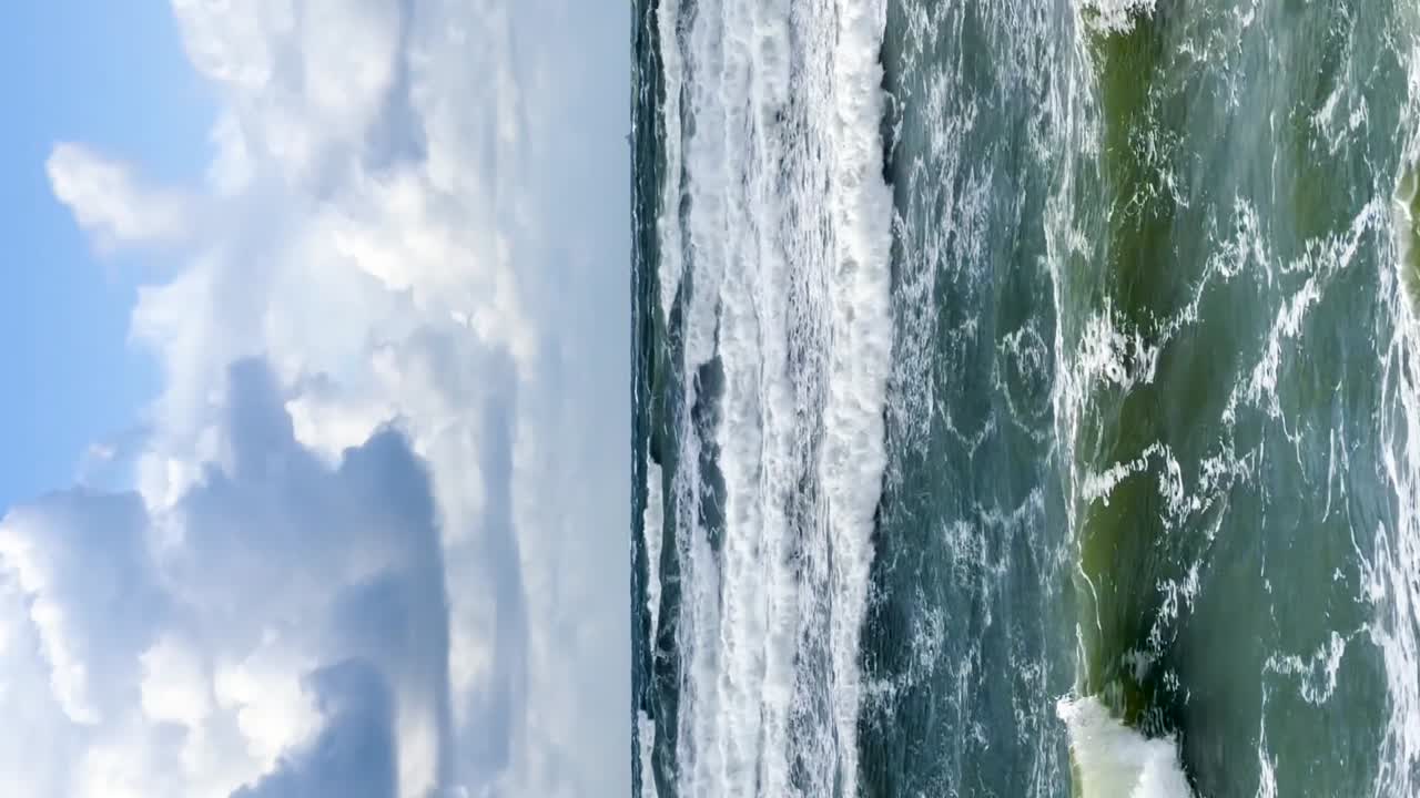 Maestosità Dinamica: Potenti onde marine che si infrangono sulla costa di Palanga, Lituania, su uno sfondo di cieli blu e nuvole