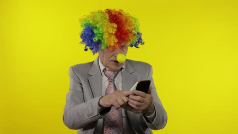 el payaso empresario independiente pierde dinero mientras juega juegos en línea en el teléfono