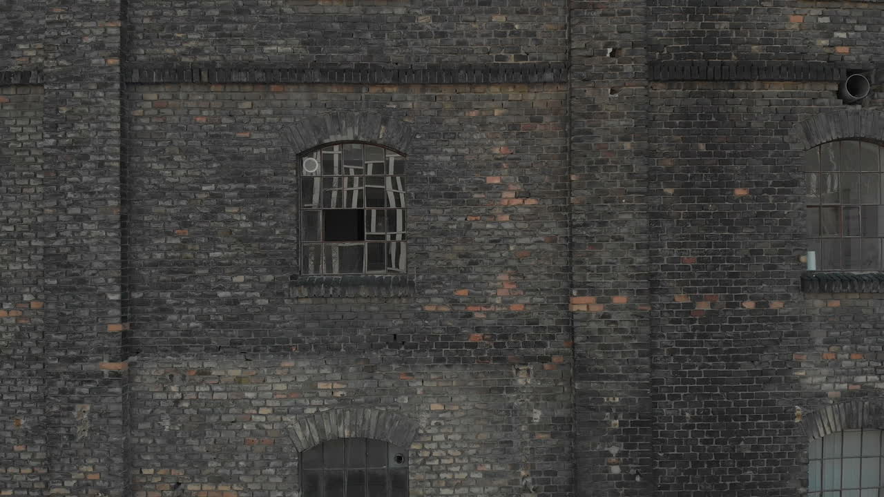 왼쪽으로 패닝하는 공중 촬영, 현대 건물을 반사하는 거대한 창문이 있는 벽돌 벽 앞으로 날아가는 모습