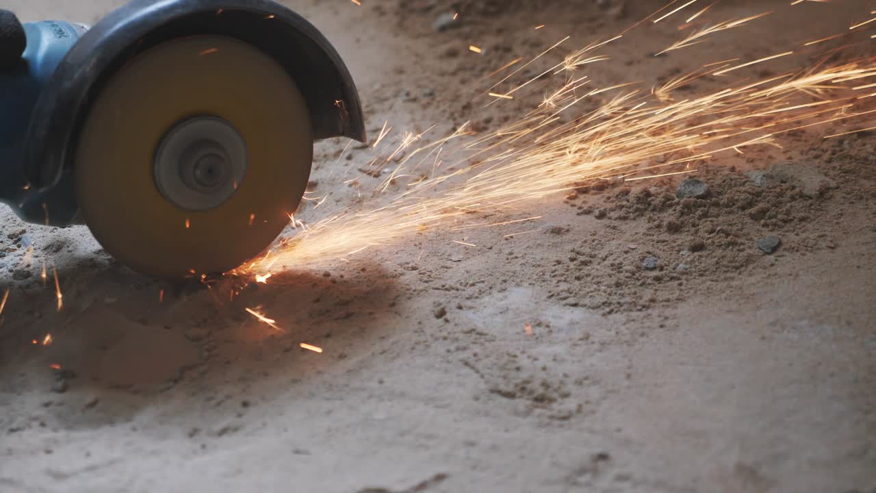 오렌지 스파크와 함께 원형 도자기로 금속 튜브를 자르는 노동자 손. 건설 개념. 원형 손 도자기에 의해 금속을 자른 노동자. 느린 동작.