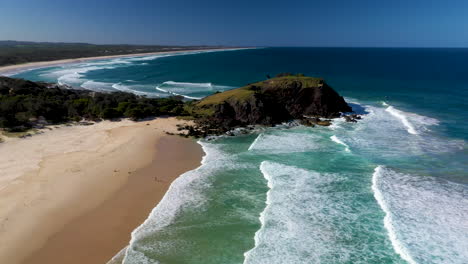 wide revealing drone shot of shoreline and rock outcropping at cabarita beach australia