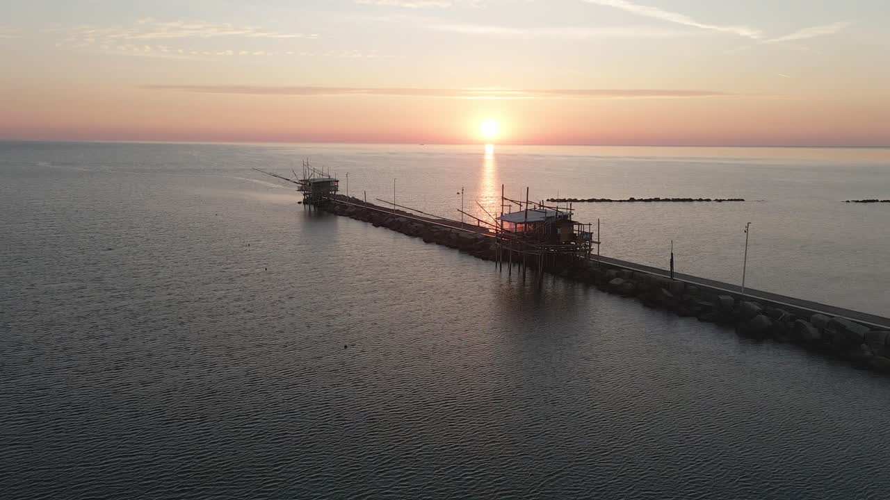 Vista aerea paesaggistica di una silhouette di trabucco, una tradizionale macchina da pesca, sulla costa italiana, al tramonto.
