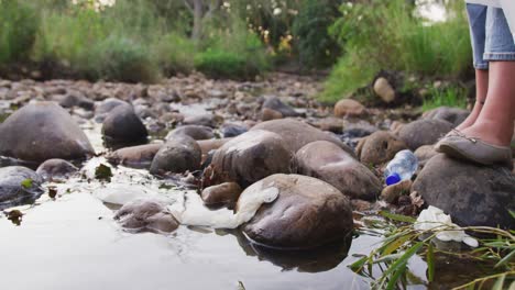 sección baja de la mujer limpiando el río en un bosque