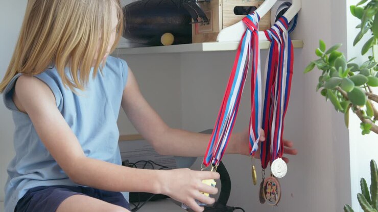 Bambino che ammira la sua collezione di medaglie sportive