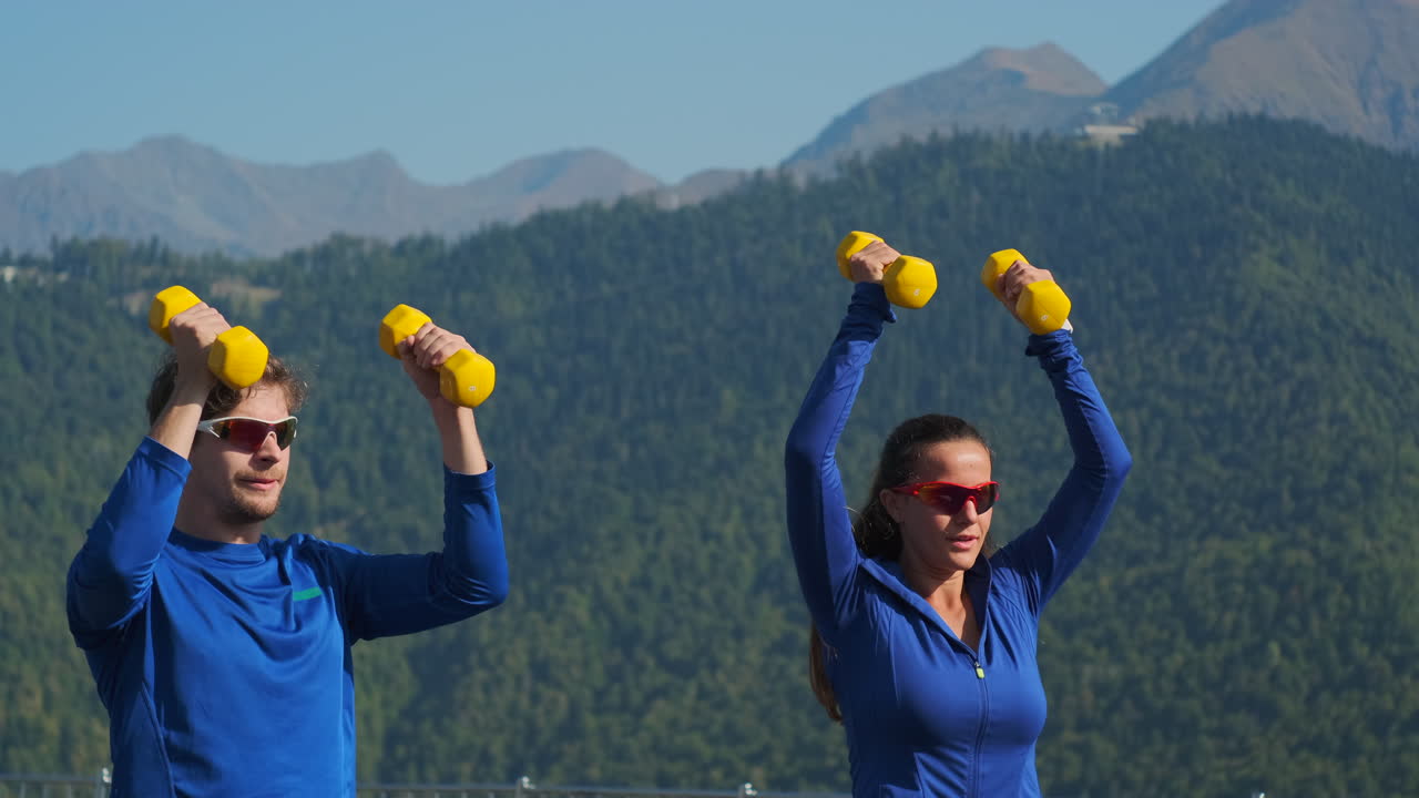 pareja haciendo ejercicio con pesas en las montañas