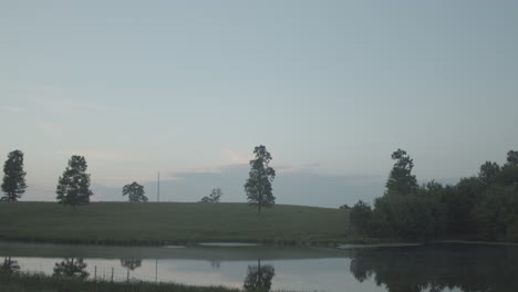 a tilt down from the blue sky reveals a dusky sunset near a country pond.
