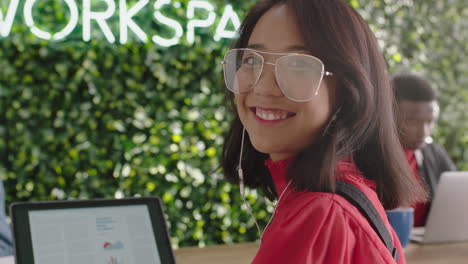 Retrato-Lindo-Joven-Mujer-De-Negocios-Asiática-Estudiante-Sonriendo-Disfrutando-De-Una-Carrera-Exitosa-En-Una-Oficina-Moderna-Y-Moderna-Usando-Una-Computadora-Portátil-Escuchando-Música-Con-Gafas