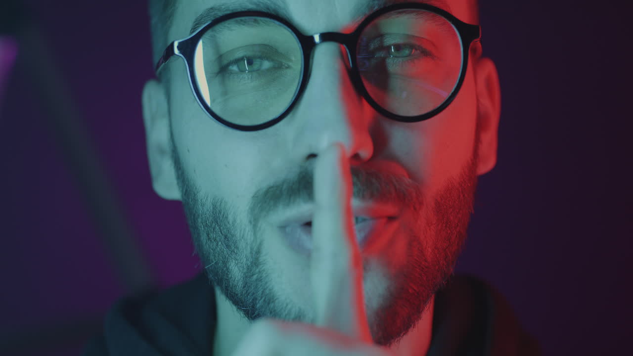 Man with glasses and finger to lips