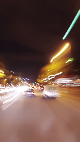 driving around barcelona at night with the city lights and traffic in vertical