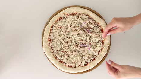 Woman-Hand-Adding-Onions-On-Top-Of-A-Homemade-Pizza