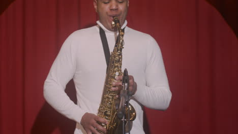 vista frontal del hombre latino tocando el saxofón durante la actuación de música en vivo