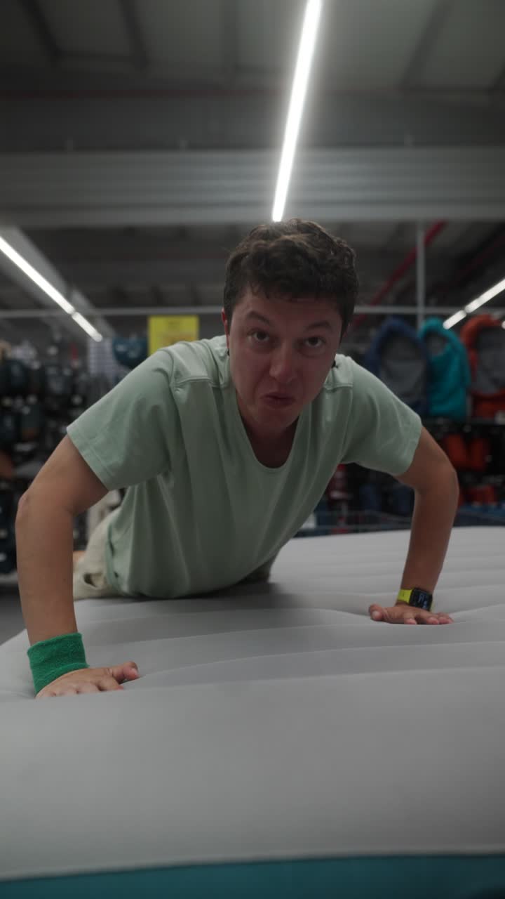 Man Testing an Air Mattress in a Sporting Goods Store