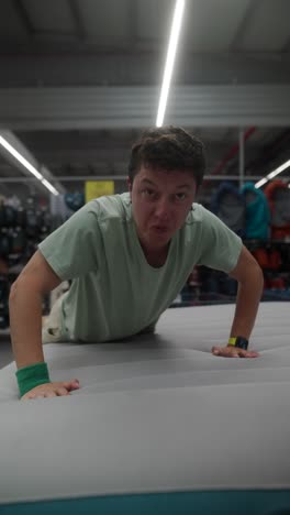 man testing an air mattress in a sporting goods store